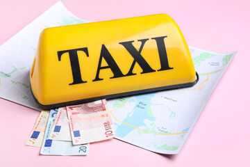 Yellow taxi roof sign, map and Euro banknotes on pink background