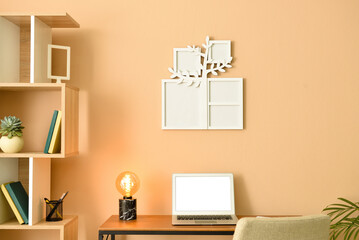Cozy interior of modern workplace with laptop and family tree photo frame