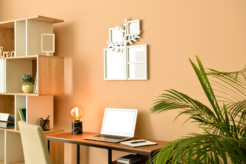 Cozy interior of modern workplace with laptop and family tree photo frame