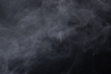 Dense Fluffy Puffs of White Smoke and Fog on black Background, Abstract Smoke Clouds, Movement Blurred out of focus. Smoking blows from machine dry ice fly fluttering in Air, effect texture