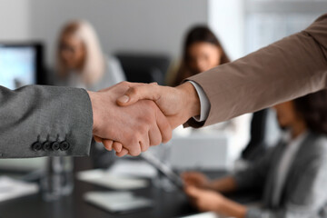 Male colleagues shaking hands during meeting in office, closeup