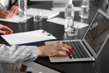 Mature businesswoman working with laptop during meeting in office, closeup