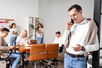 Handsome business man talking by mobile phone in office