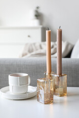 Candles and cup of tea on white table, closeup