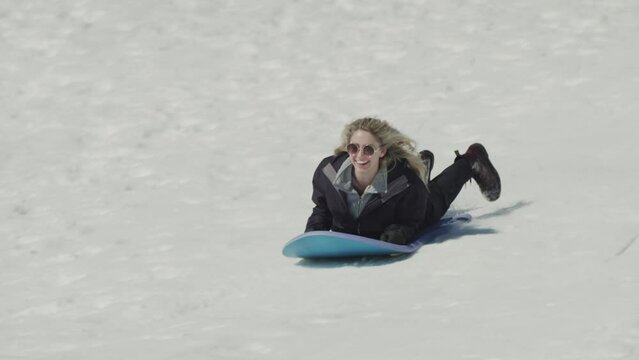 Smiling girl riding sled on snowy hill / Tibble Fork, Utah, United States