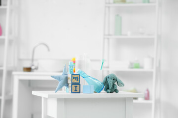 Fototapeta na wymiar Bath accessories for children and different toys on white table in light bathroom