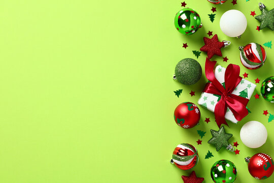 Red and green Christmas decorations on light green background. Christmas frame. Flat lay, top view, copy space.