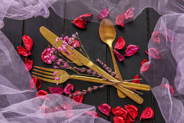 Cutlery and floral decor on dark wooden background