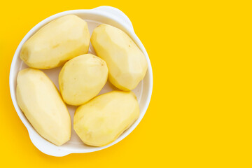 Raw peeled potatoes on yellow background