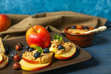 Plate of fresh apples with nut butter and blueberry on color wooden table, closeup