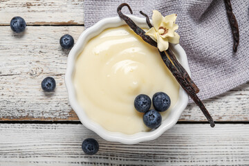 Ramekin of delicious vanilla pudding on light wooden background, closeup