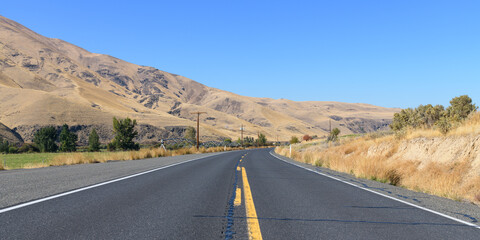 State Route 821 passing through the Yakima Canyon in Central Washington State with road passing barren hills and occasional farmland