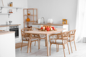 Dining table with pumpkins, candles and pampas grass in light kitchen
