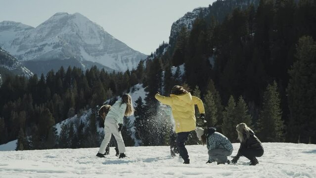 Wide shot of playful girls in field having snowball fight / Tibble Fork, Utah, United States