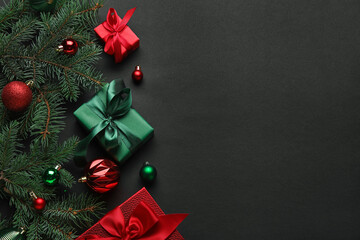 Composition with fir branches, Christmas gifts and balls on black background