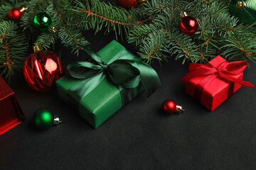 Composition with fir branches, Christmas gifts and balls on dark background, closeup