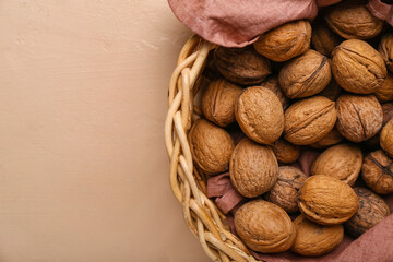 Basket with fresh walnuts on color background, closeup