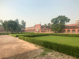 Agra, India, November 2019 - A large brick building with grass and trees