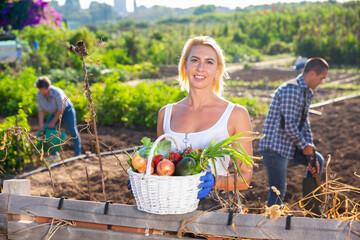 Obraz premium Portrait of young female amateur farmer with harvested vegetables and greens in garden