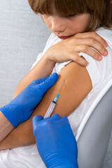 vaccination of children, a little boy at a doctor's appointment, an injection in the arm, children's medicine, an injection in the arm, vertical photo