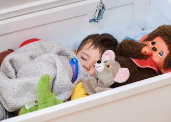 beautiful baby toddler fell asleep in a box with his soft toys