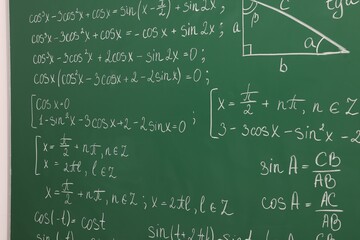 Many different math formulas written on green chalkboard