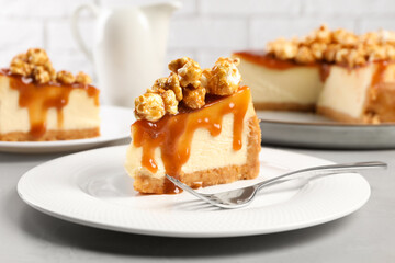 Piece of delicious caramel cheesecake with popcorn on light grey table, closeup