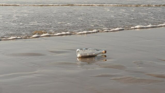 A message in a bottle washed up on the beach by waves