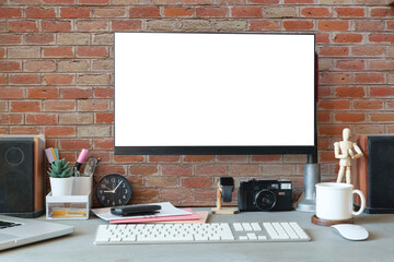 Stylish workplace with computer, camera, stationery and coffee cup. Blank screen for your design.