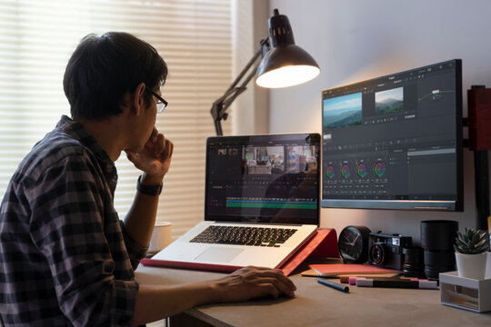Male freelancer editing video on computer with professional program in home office.