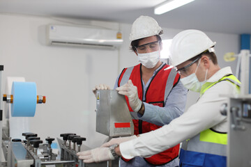 Caucasian mechanic technician maintenance, repairing industrial machinery equipment in factory. Professional worker in protective clothing with goggles and mask using wrench at manufacturing factory