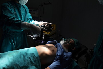 Closeup image of professional concentrated surgical team performing CPR with defibrillator on...