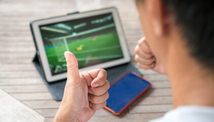 Man with thumbs up while watching football sports game on digital tablet. Live stream or sports...