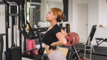 Fototapeta na wymiar Candid scene of a young asian woman checking her figure while warming up at the gym.