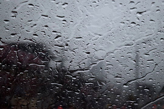 Raindrops on the windshield of the car. Raindrops form an abstract illustration on a car window. Driving a car in the rain
