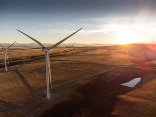 Aerial sunset view of working windmills producing sustainable energy near Pincher Creek Alberta Canada.