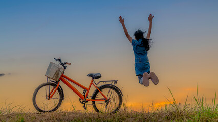 Two happy kids jumping on hills against sky  sunset