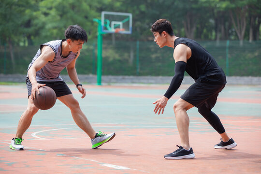Happy young men playing basketball outdoors