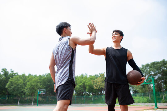 Happy young men playing basketball outdoors