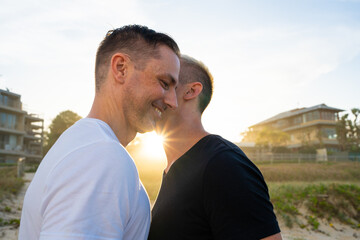 gay couple whisper in ear for sunset on beach
