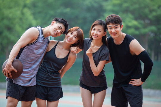 Happy young friends playing basketball outdoors