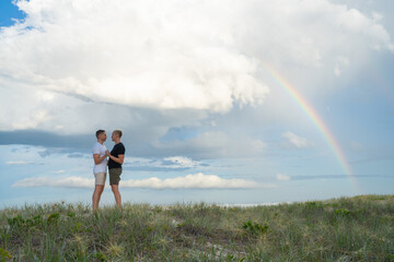 Fototapeta na wymiar gay couple dancing with rainbow at beach