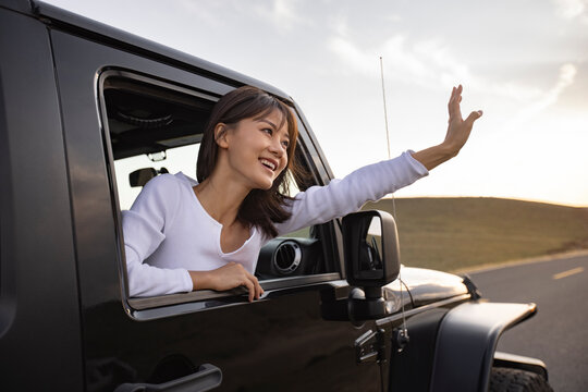 Happy young woman looking out of car window