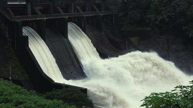Hydroelectric dam on the river with water overflowing the dam after heavy rain 4k video footage.