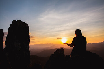 silhouette of man rise hand up praying  on top of mountain and sunset sky abstract background. Freedom and travel adventure concept.