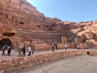 Petra, Jordan, November 2019 - A group of people walking in a canyon with Petra in the background