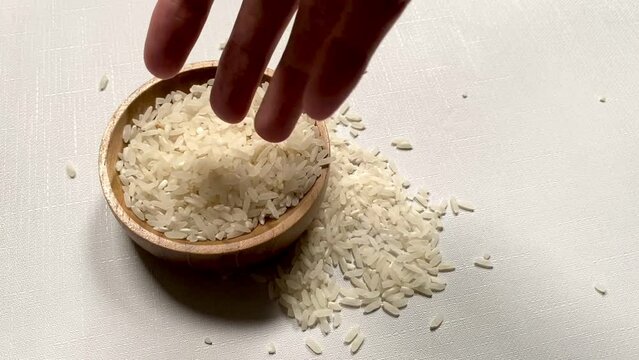 woman asian hand touching white rice grain on a wooden bowl in white background. copy space close up