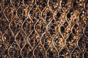 Selective focus macro of a dirty kitchen range hood filter clogged with grease.