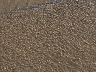 A transparent sea wave running over the sand