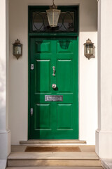 Green front door with two light fixtures